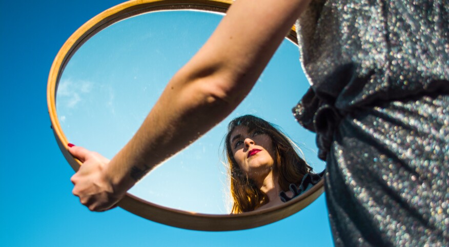 Woman holding mirror and looking at her reflection