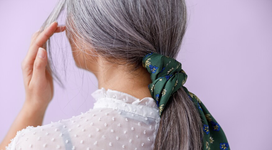 Woman from behind brushing back her beautiful gray hair