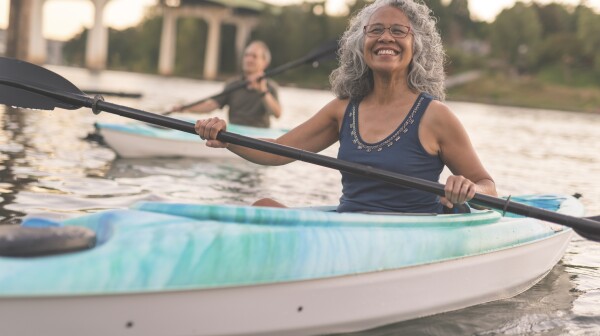 An ethnic senior woman smiles while kayaking with her husband