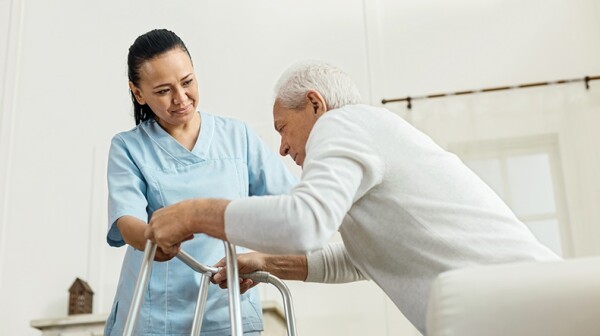 Nurse helping older man with a walker 