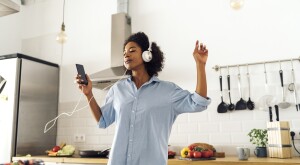 Woman dancing and listening music in the morning in her kitchen