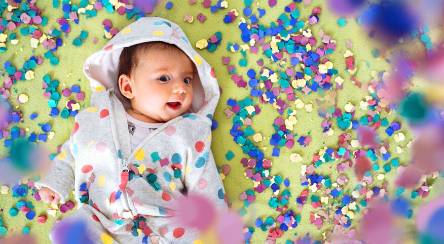 Happy baby girl surrounded by confetti