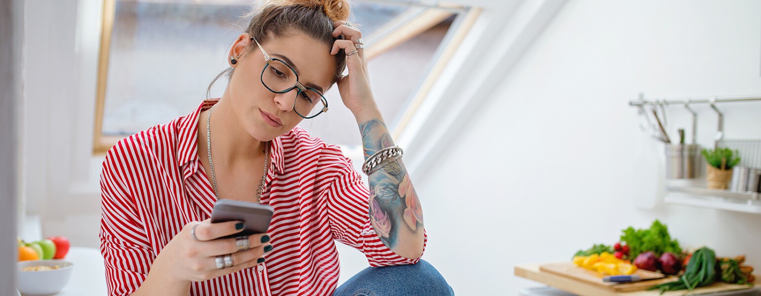 woman who is upset looking at phone after seeing her ex husband unfriended her on facebook