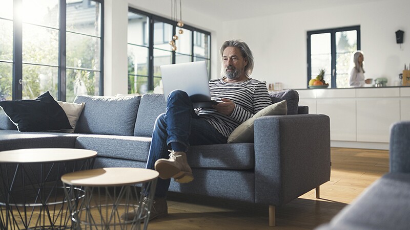 A man sitting on a couch with a laptop on his lap