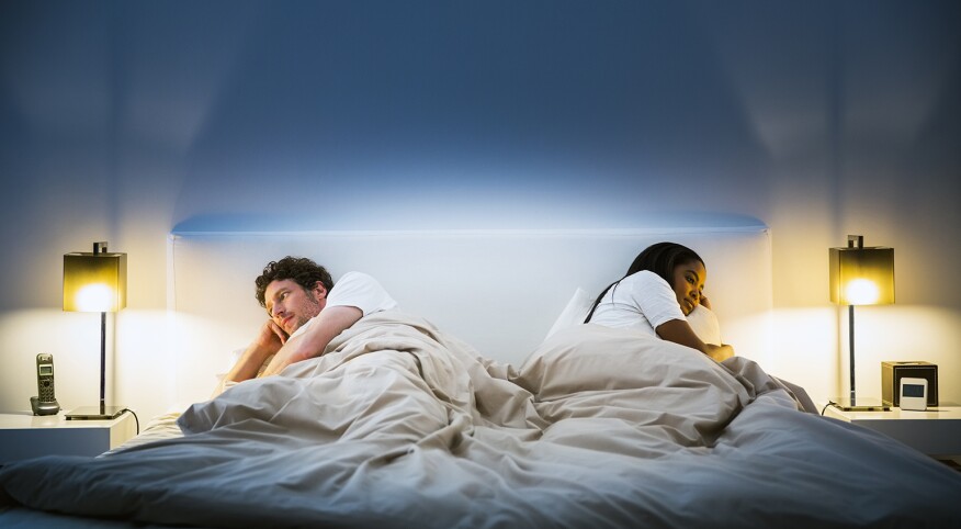 couple lying in bed facing opposite directions