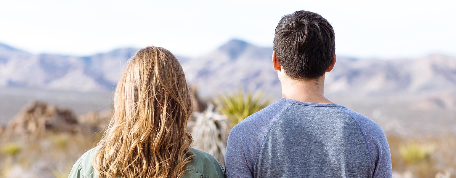Male and female friends overlooking mountain scenery.
