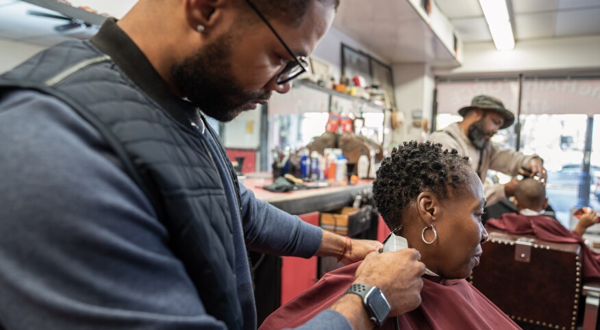 Mature Black woman getting haircut in barber's chair