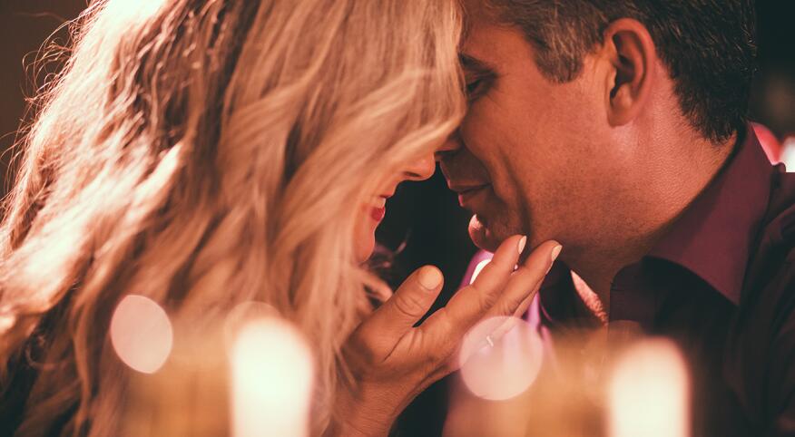 Woman's hand on man's face about to kiss