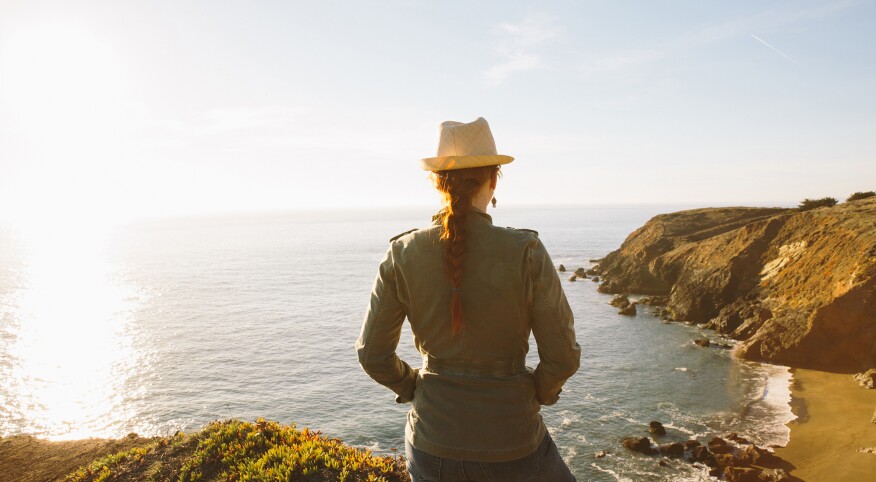 Woman in nature looking at view of pacific ocean