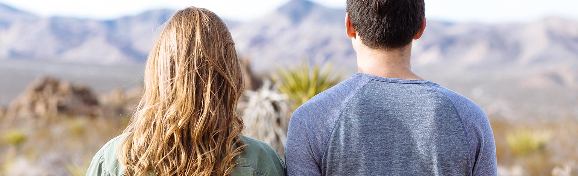 Male and female friends overlooking mountain scenery.