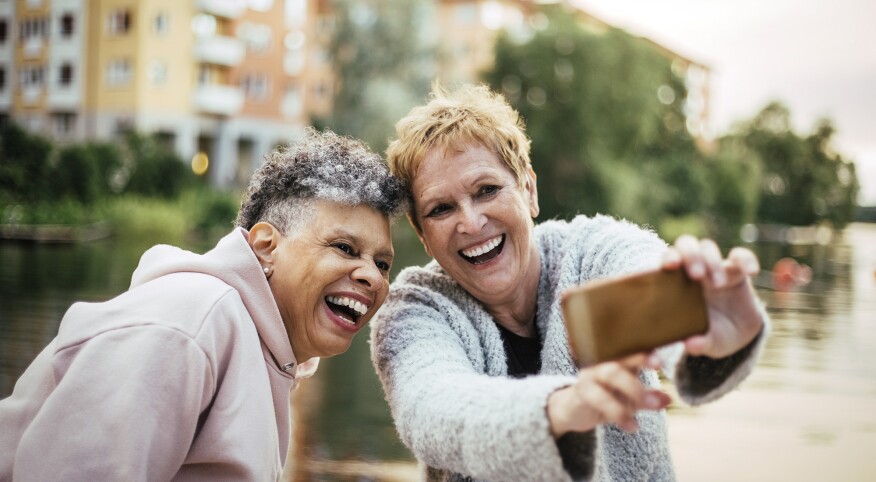 Smiling women enjoying while photographing through smart phone during picnic