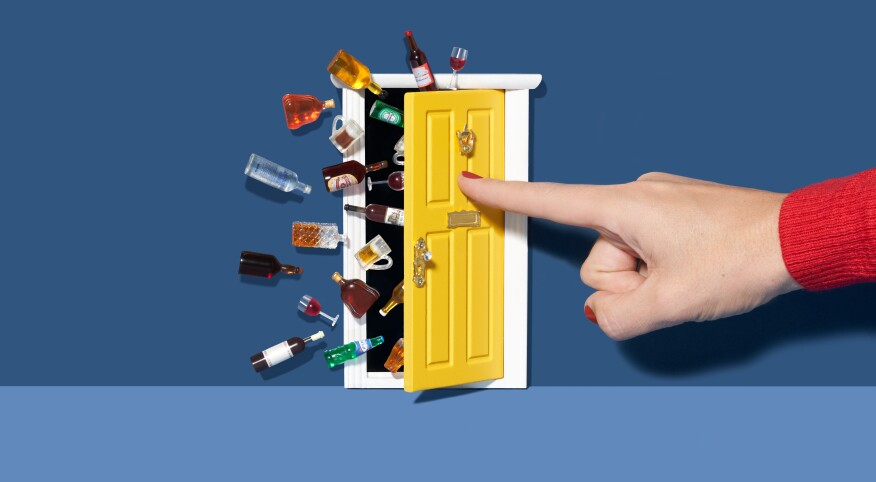 Woman's hand pushing a door closed that's spilling out with alcohol bottles and beverages 