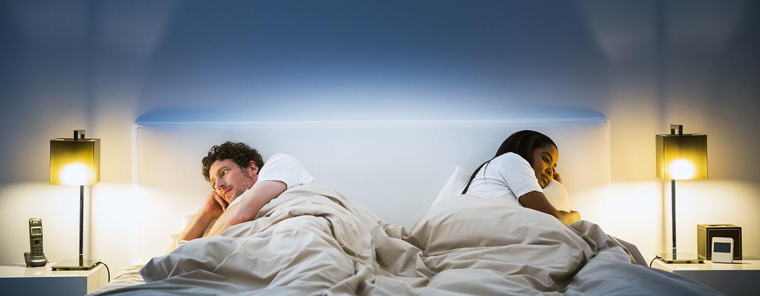 couple lying in bed facing opposite directions
