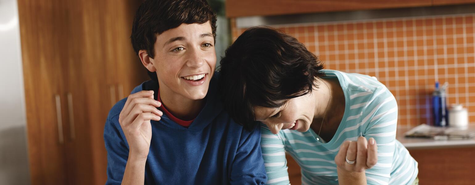 Mother and her teenage son laughing in their kitchen