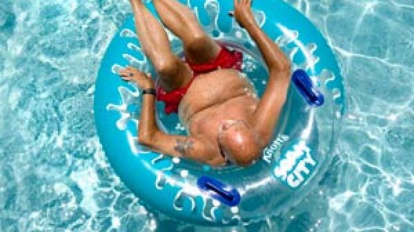 Man lounges in a pool. Heat wave can be dangerous for boomers and seniors