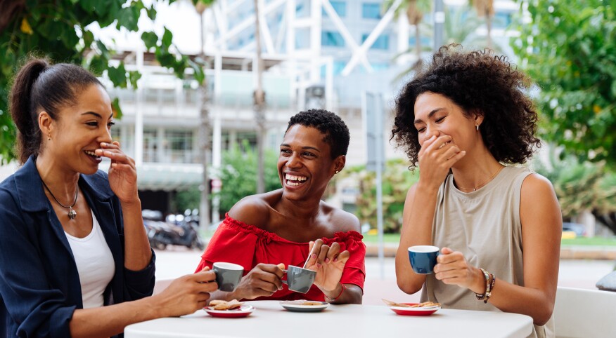 3 women having a laugh outside at a coffee shop