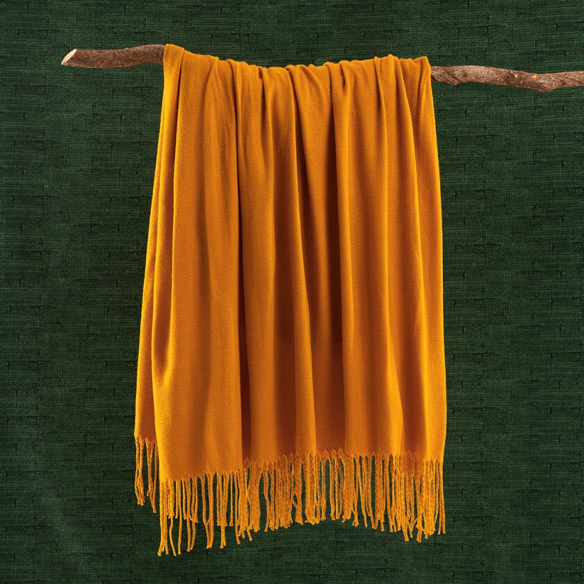 marigold blanket hanging on a tree branch in front of a green background