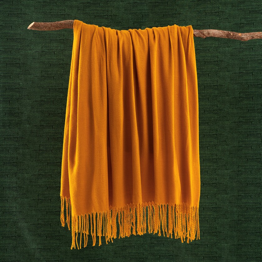 marigold blanket hanging on a tree branch in front of a green background