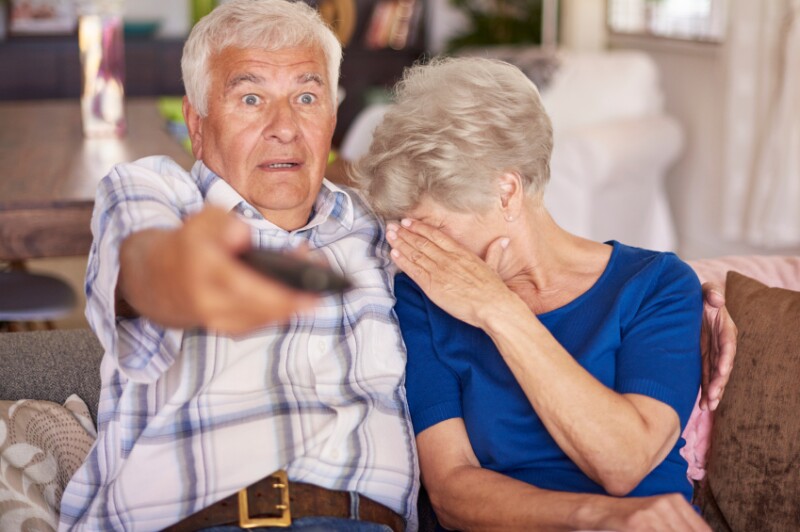 Senior couple watching a horror movie on television