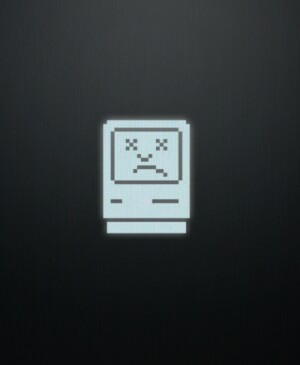 Computer screen depicting the vintage Macintosh operating system sad face icon