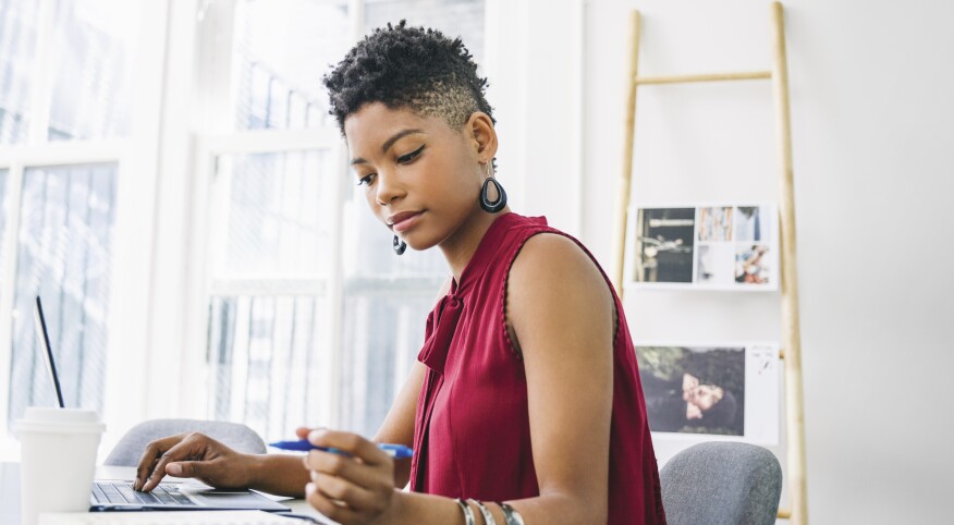 A woman wears a natural hair style while working at a desk.