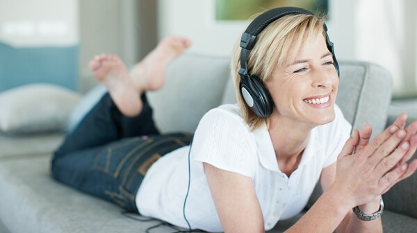 A woman with headphones on lying on the couch
