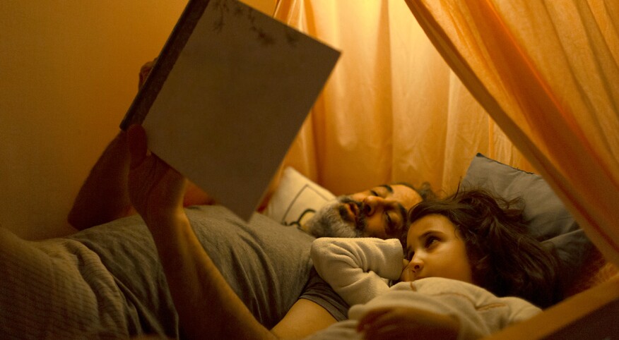 Father reads to daughter before bedtime