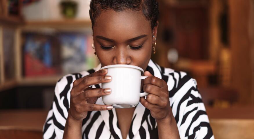 Woman in zebra striped shirt drinks from a mug