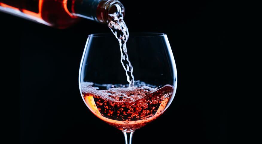 High contrast bottle of wine being poured into a glass with black background