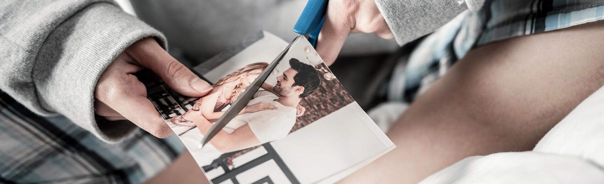 woman cutting photo of her and her ex in half