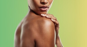 Woman with no shirt and back towards camera, on green and yellow background