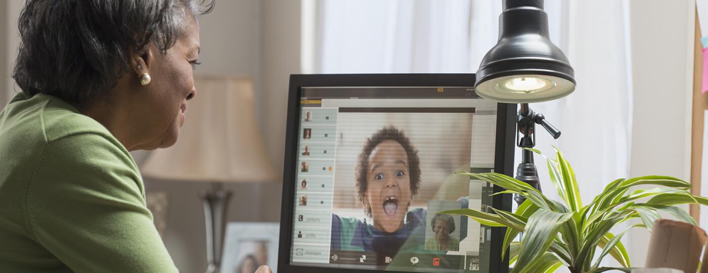 Black woman video conferencing with grandson on computer