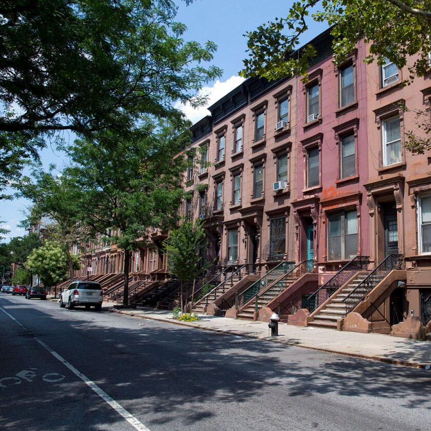 Brownstone buildings stand in central Harlem, New York City.