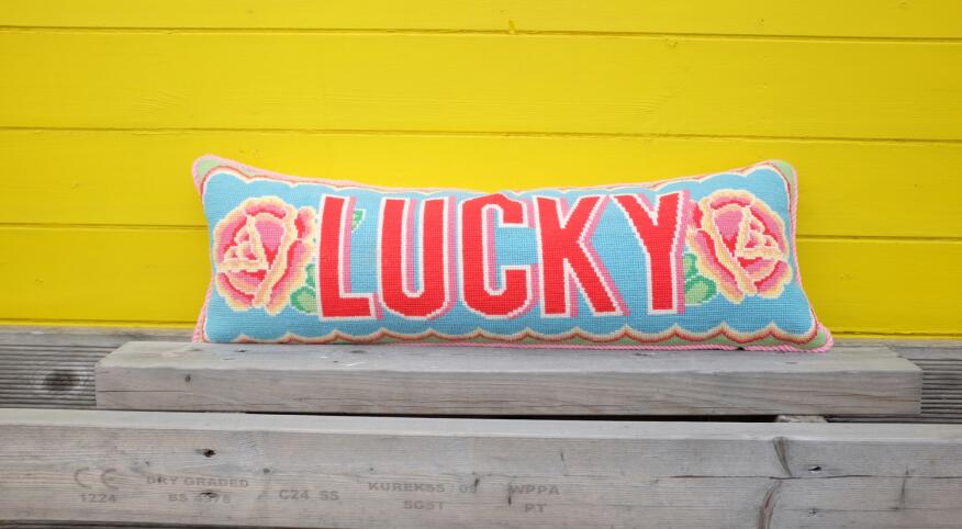 Needlepoint pillow with the word "lucky" on it by Emily Peacock