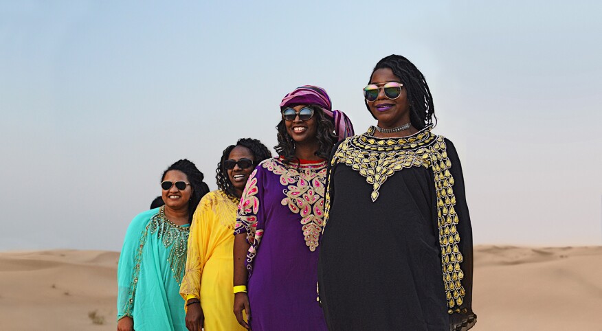 A group of four women stand in the UAE desert near Abu Dhabi.