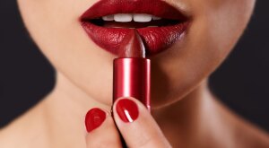 Closeup image of a woman applying lipstick.