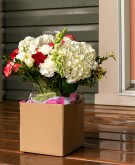A box with a flower bouquet on a front porch in front of the door