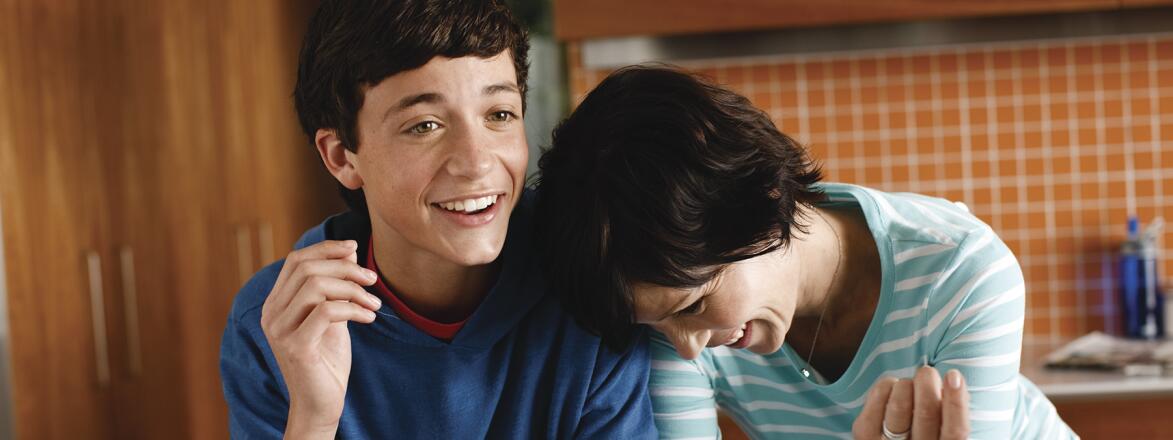 Mother and her teenage son laughing in their kitchen