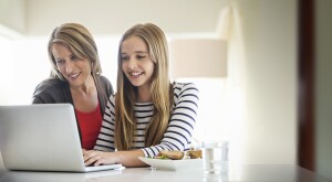 mother and daughter using a laptop together at home