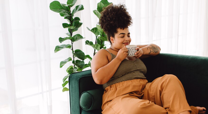 Woman sitting out couch relaxing and drinking coffee