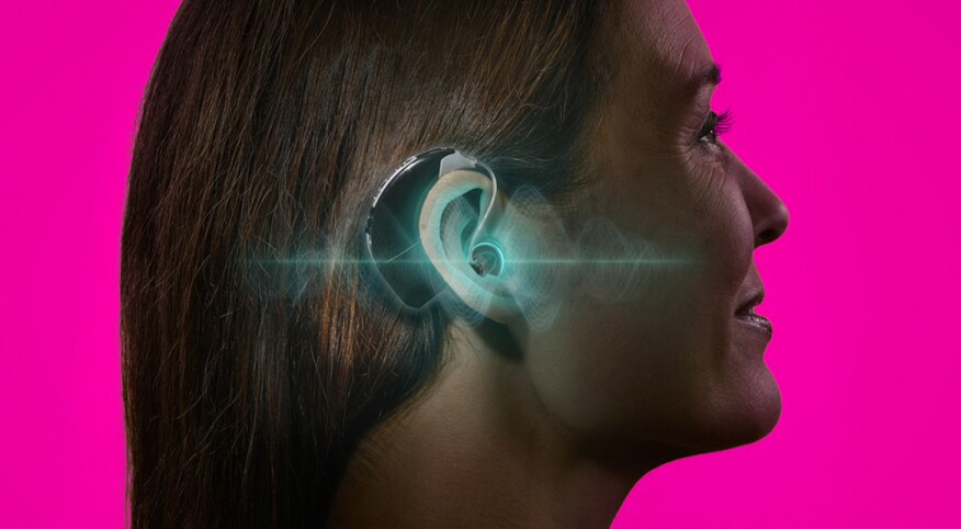 Woman with hearing aid, pink background