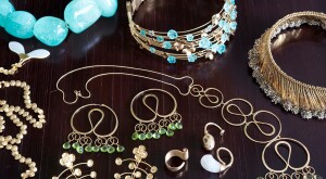 Gold jewelry with blue and green gemstones on dark brown wood surface