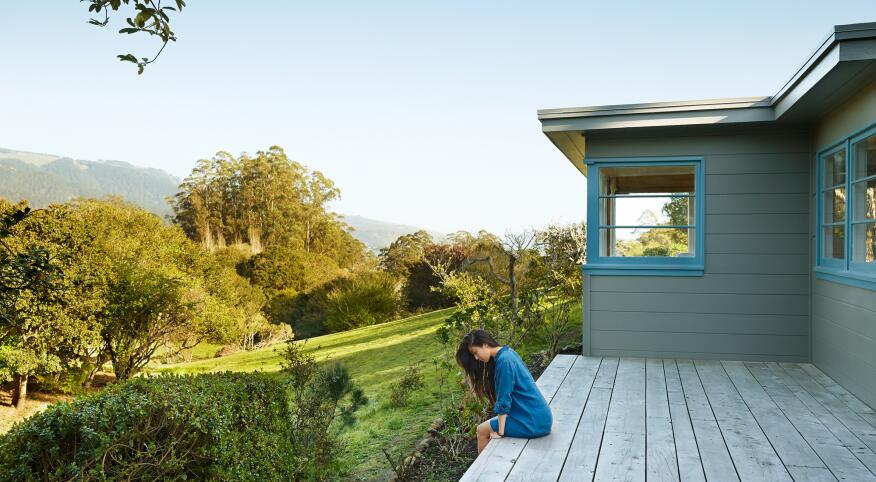 Woman sitting alone on her back porch surrounded by nature