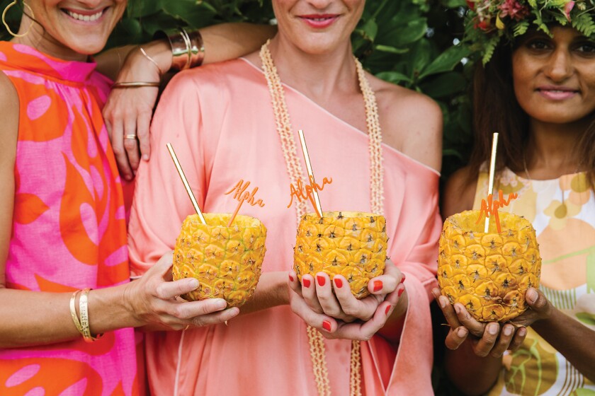 Three women with pineapple drinks at Hawaiian-themed party