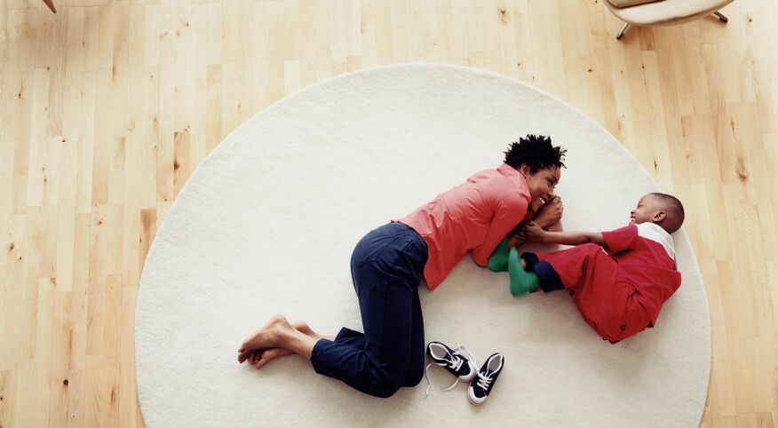 Mother and son (3-5) lying on rug, smiling, overhead view