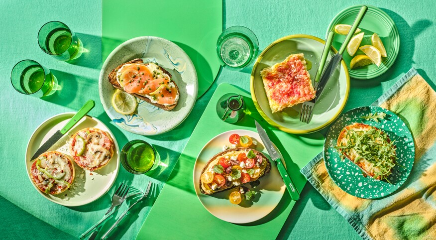 Overhead photo of five slices of open faced toast on bright green background