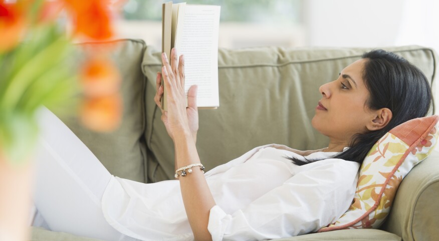 Woman reading book on sofa