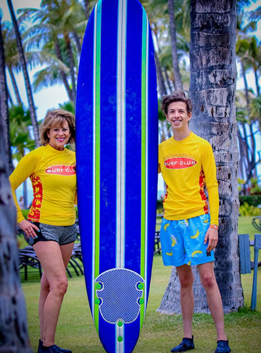 Kerrie Houston Reightley posing with her son and a surf board