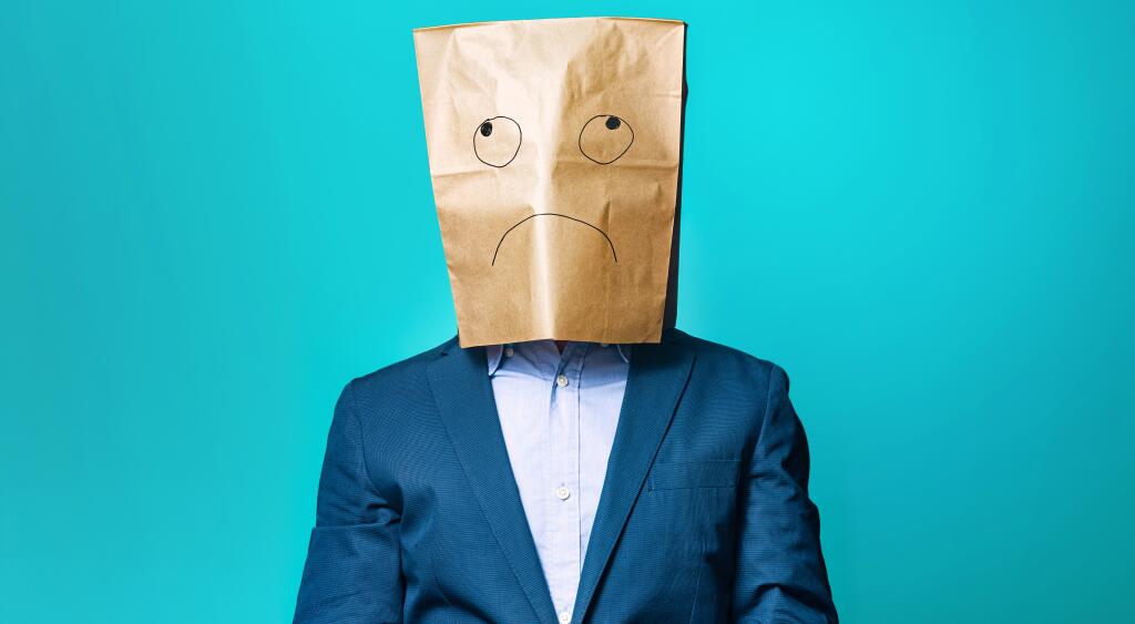 photo of man with paper bag over his head that has sad face drawn on it