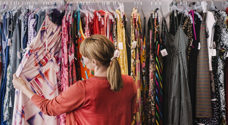 Woman looking at dress hanging on rack while standing at store